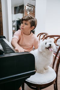 Child enjoying music with a fluffy dog at home, highlighting friendship and creativity.