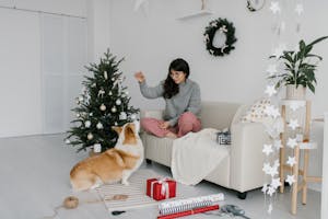 Festive setting with a woman and her Corgi celebrating Christmas indoors with decorations.