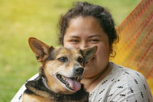 Portrait of a Latina woman with her dog. The dog is happy with his tongue out.